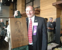 Craven next to his Hall of Fame plaque on the day he was inducted into the Wisconsin Conservation Hall of Fame, Stevens Point, WI. 2019. (Photo courtesy of Tim Eisele.)
