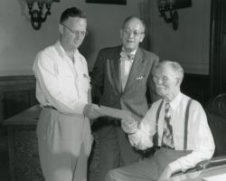 Ernest Swift, Wisconsin Conservation Department Director presenting check of $457,115.00 to Secretary of State, F. R. Zimmerman with and State Treasurer Smith looking on. The check is payment for the froesty land in the Flambeau forest and is the single largest purchase ever by the Wisconsin Conservation Department with approximately 1,776 acres of virgin timber. 1951. (Photo courtesy of Wisconsin DNR.)