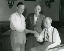 Ernest Swift, Wisconsin Conservation Department Director presenting check of $457,115.00 to Secretary of State, F. R. Zimmerman with and State Treasurer Smith looking on. The check is payment for the froesty land in the Flambeau forest and is the single largest purchase ever by the Wisconsin Conservation Department with approximately 1,776 acres of virgin timber. 1951. (Photo courtesy of Wisconsin DNR.)